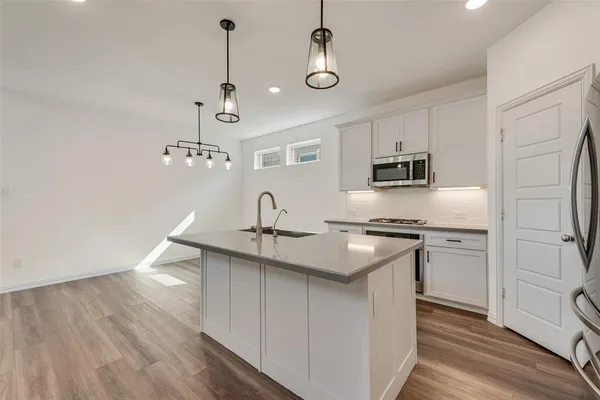 a kitchen with stainless steel appliances granite countertop a sink a stove a refrigerator and island with wooden floor