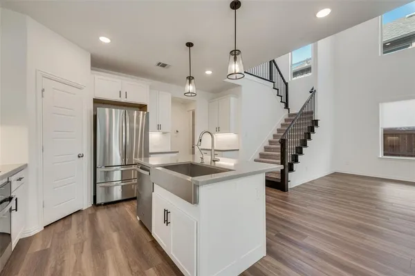 a kitchen with stainless steel appliances kitchen island a hardwood floor and a sink