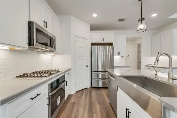 a kitchen with stainless steel appliances a sink cabinets and wooden floor