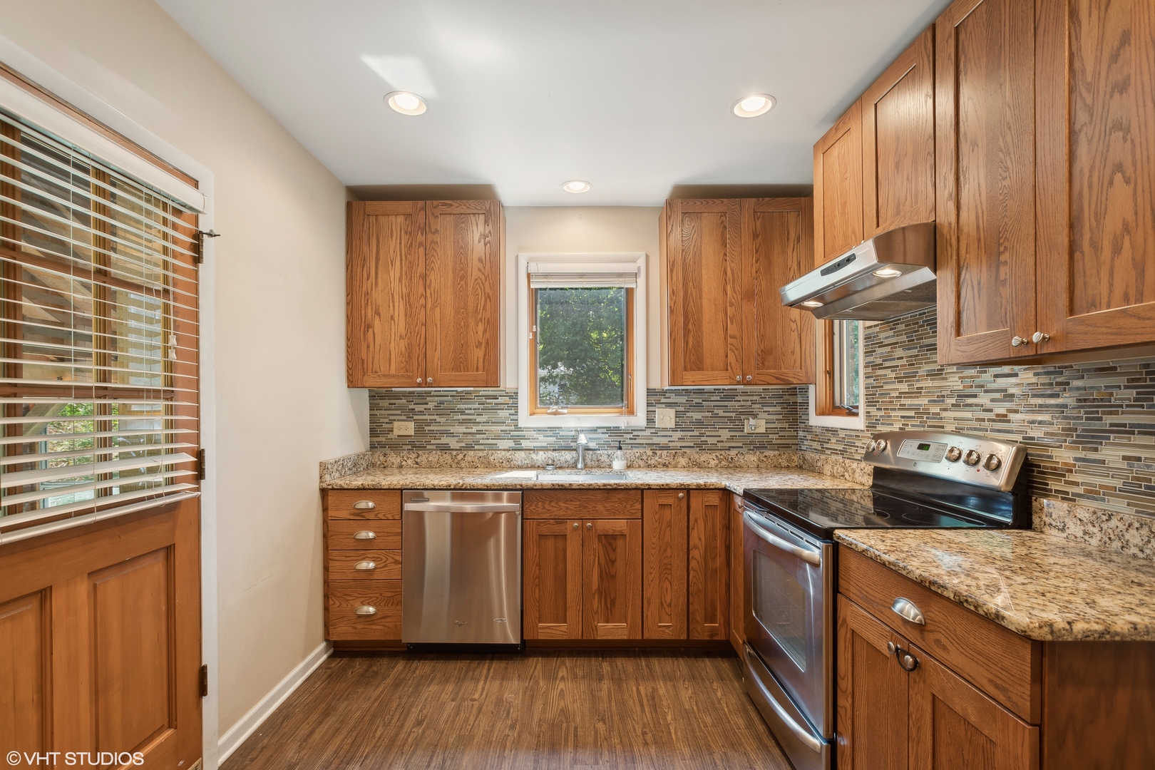 502 Raffel Road Woodstock, IL 60098 - Photo 4 of 24 a kitchen with stainless steel appliances granite countertop wooden floor sink stove and wooden cabinets