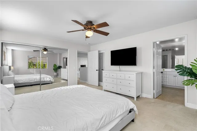 a bedroom with a bed a flat screen tv and a chandelier