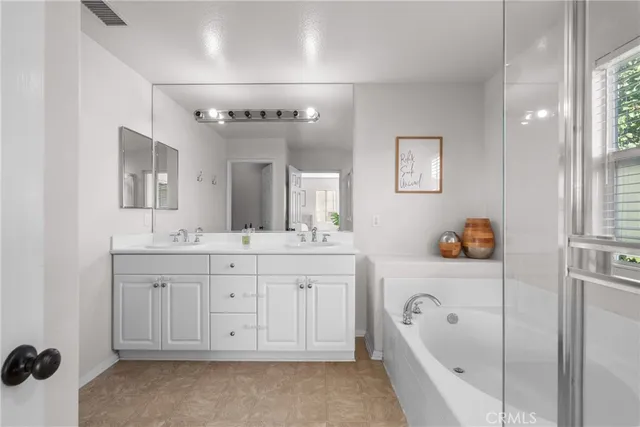a spacious bathroom with a tub sink and mirror