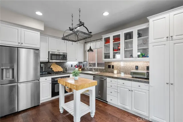 a kitchen with stainless steel appliances a sink a stove a refrigerator cabinets and wooden floor