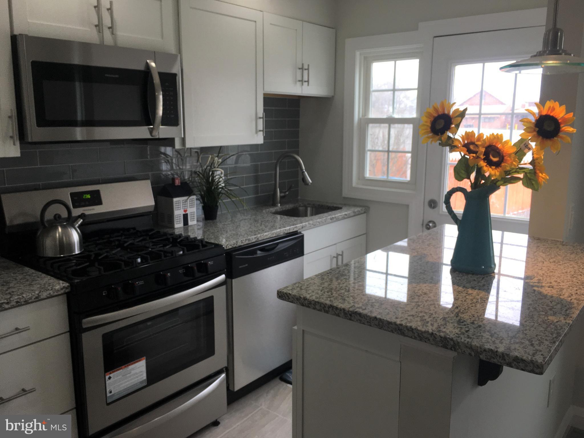 7968 Kavanagh Road Baltimore, MD 21222 - Photo 14 of 30 a kitchen with granite countertop stainless steel appliances a sink stove top oven and microwave