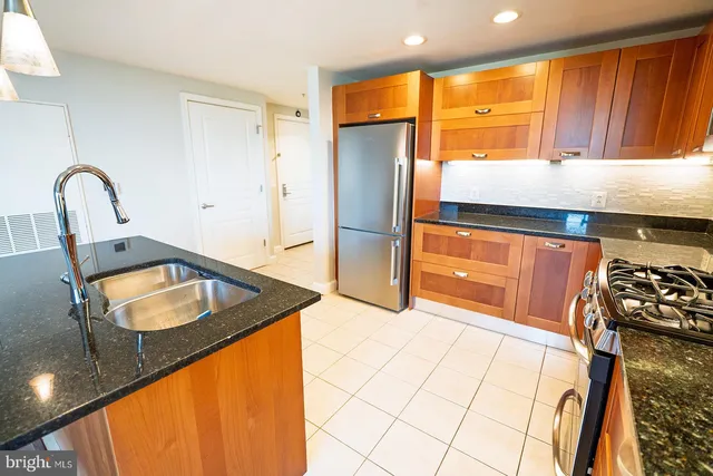 a kitchen with granite countertop a stove a sink and a refrigerator