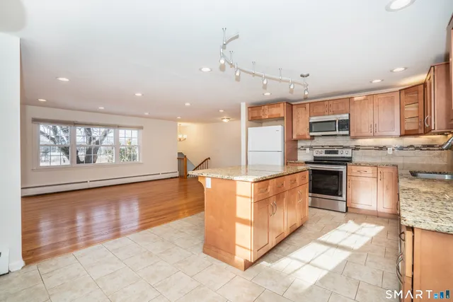 a large kitchen with stainless steel appliances kitchen island granite countertop a stove a sink and a microwave