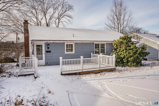 a view of a house with a wooden fence and large trees