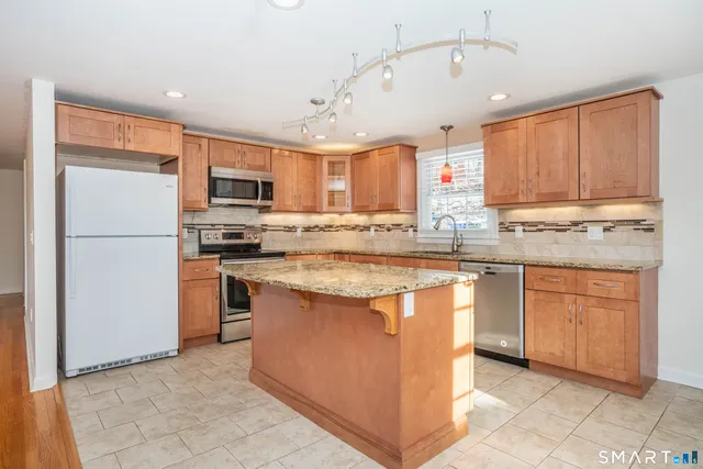 a kitchen with stainless steel appliances granite countertop a refrigerator a sink a stove a microwave and island