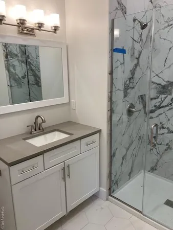 a bathroom with a granite countertop sink a mirror and shower