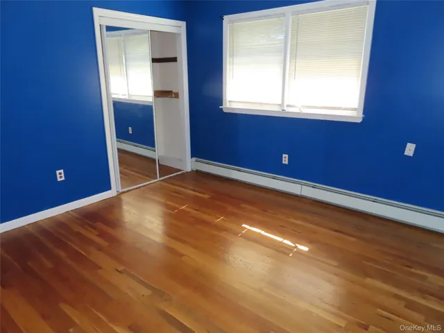 a view of empty room with window and wooden floor