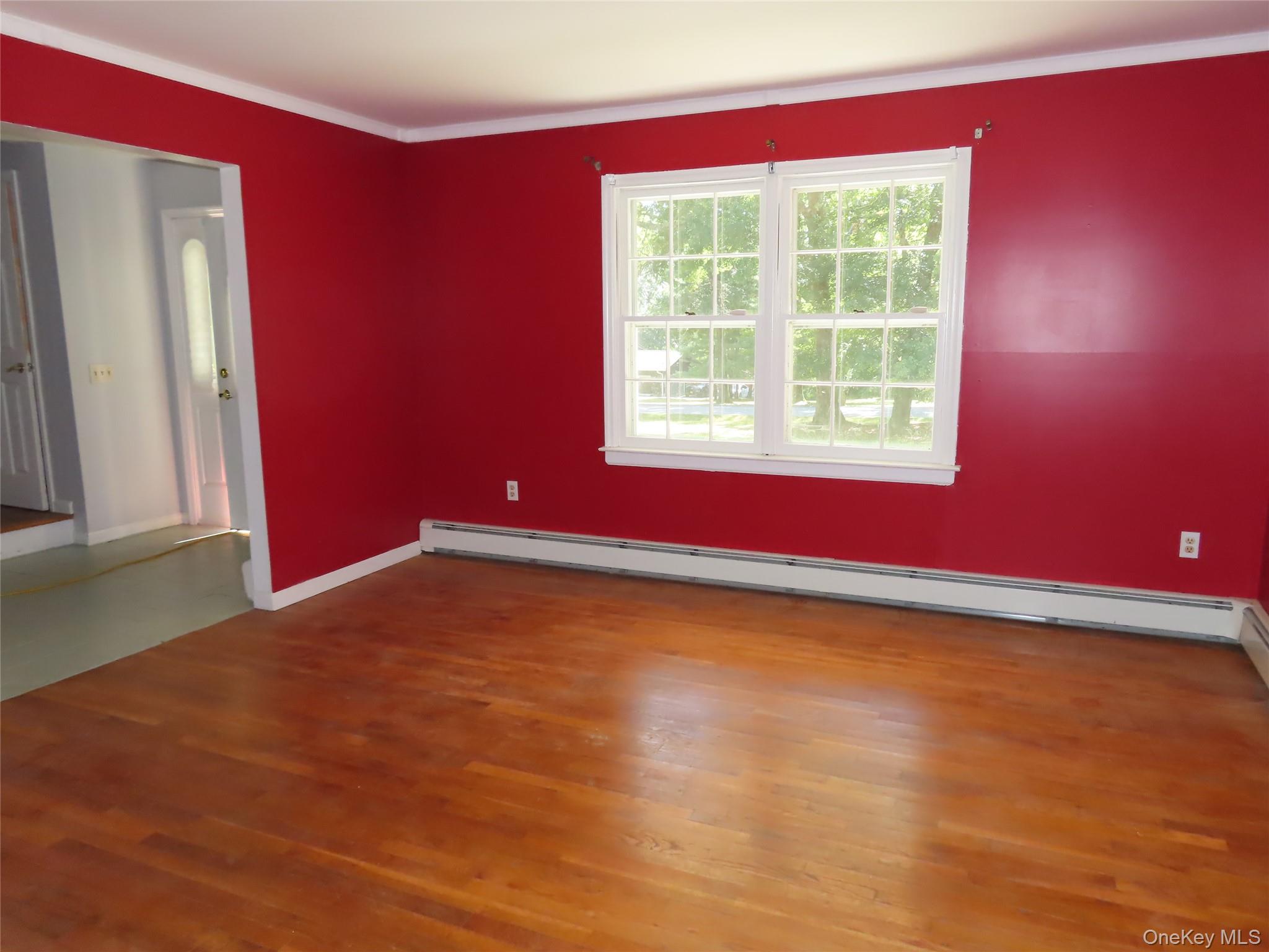 26 Darren Road LaGrangeville, NY 12540 - Photo 7 of 28 Spare room featuring a baseboard radiator, crown molding, and dark wood finished floors
