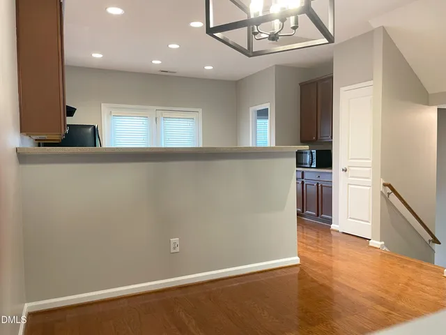 a view of a kitchen with a fridge and wooden floor