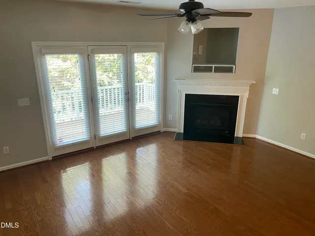 an empty room with wooden floor fireplace and windows