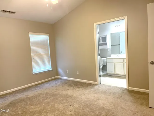 an empty room with a bathroom and a window