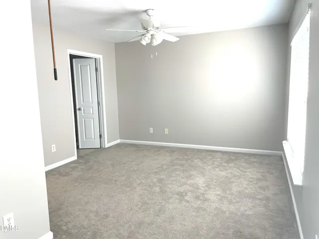 an empty room with a chandelier fan and windows