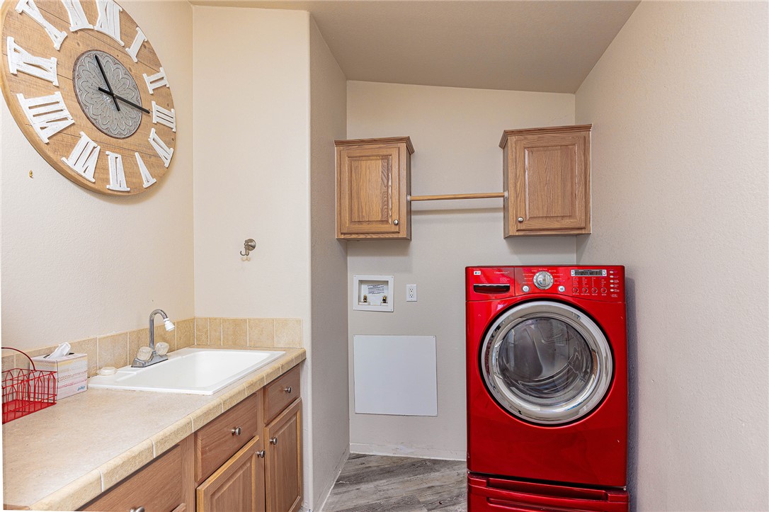 4206 Cordes Road Golden Valley, AZ 86413 - Photo 11 of 60 Utility room featuring a built-in sink with a countertop, wooden cabinetry, and durable flooring