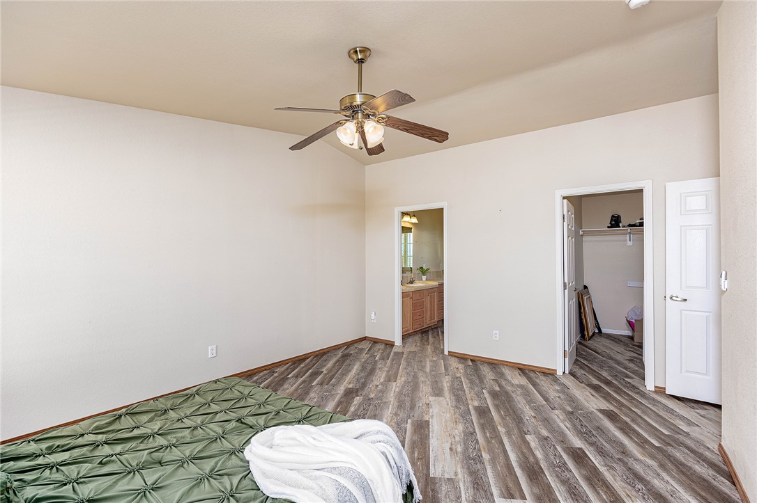 4206 Cordes Road Golden Valley, AZ 86413 - Photo 15 of 60 Bedroom featuring wood-look flooring, a ceiling fan with integrated lighting, and a doorway leading to a bathroom with a vanity