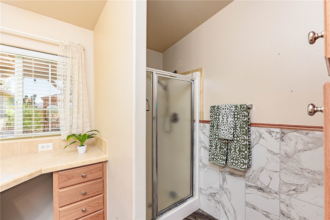 4206 Cordes Road Golden Valley, AZ 86413 - Photo 18 of 60 This bathroom features a shower with a clear glass enclosure, a window with blinds, and white marble-style wall tiling