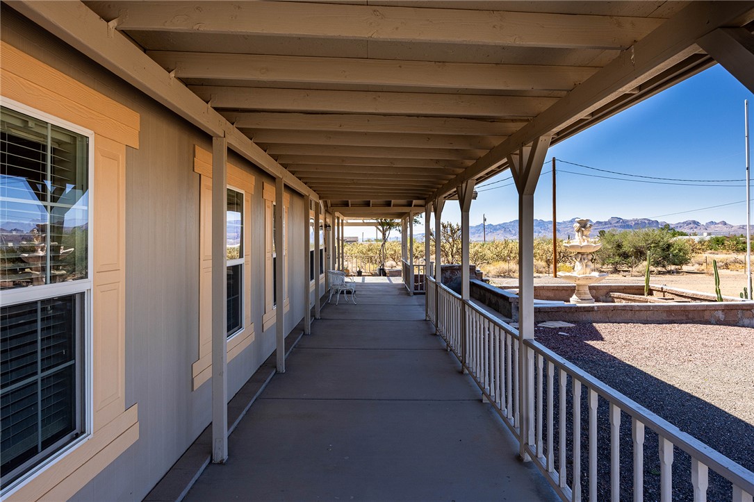 4206 Cordes Road Golden Valley, AZ 86413 - Photo 24 of 60 The property features an extensive covered porch with white railings and a desert landscape view