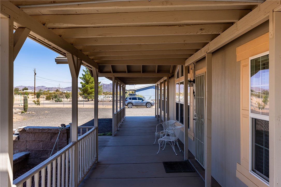 4206 Cordes Road Golden Valley, AZ 86413 - Photo 25 of 60 The property features an extensive covered porch with a railing and open views of the surrounding landscape and distant mountains