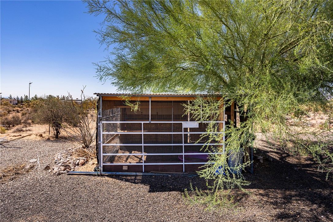 4206 Cordes Road Golden Valley, AZ 86413 - Photo 35 of 60 The property includes a fenced outdoor structure with a corrugated metal roof and a tree with green foliage providing shade