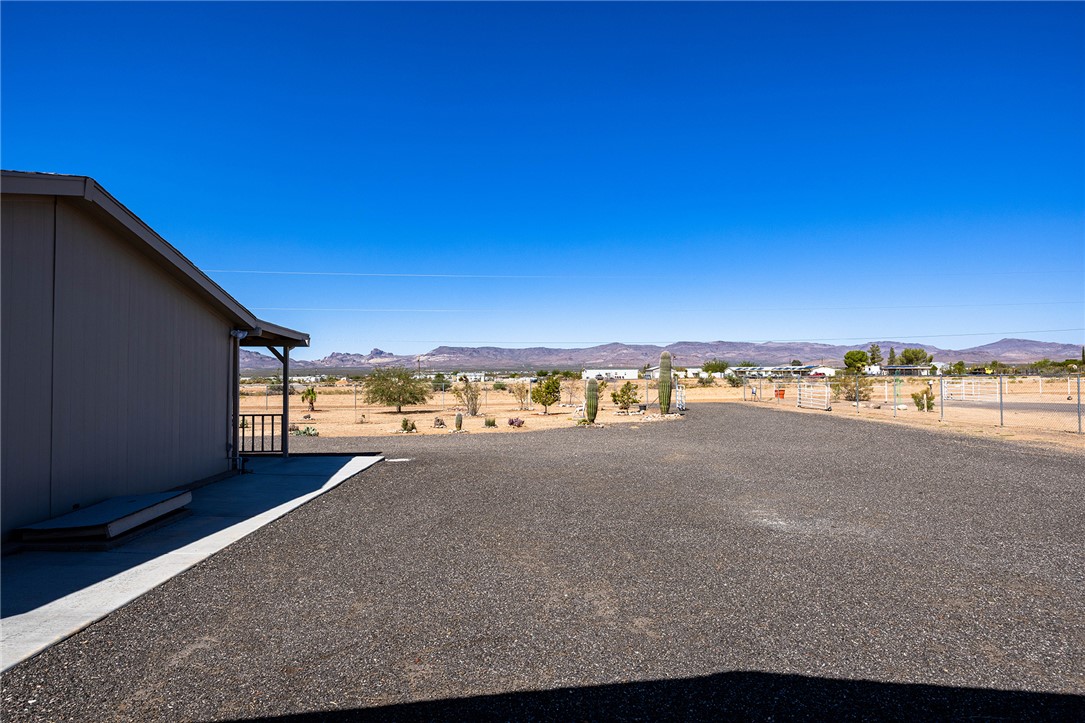 4206 Cordes Road Golden Valley, AZ 86413 - Photo 40 of 60 This property features a spacious gravel driveway, an exterior with light-colored siding, and a covered porch with railings