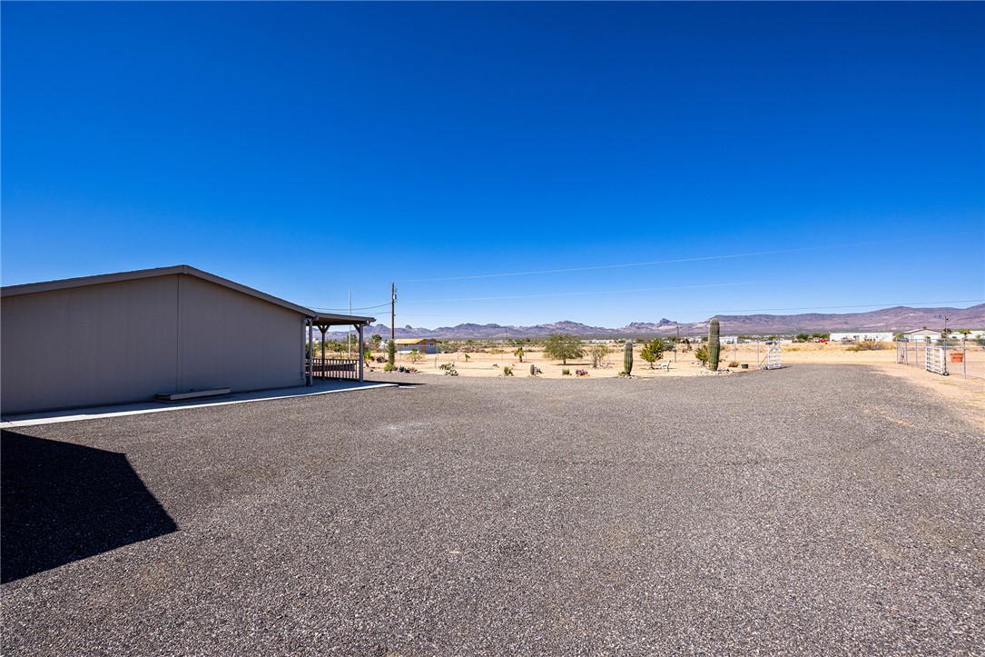 4206 Cordes Road Golden Valley, AZ 86413 - Photo 41 of 60 The property features a large gravel lot, a building with a covered patio area, and desert landscaping including cacti and trees