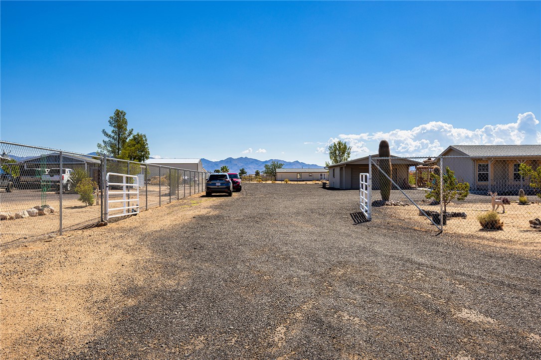 4206 Cordes Road Golden Valley, AZ 86413 - Photo 43 of 60 The property features an extensive gravel driveway, chain-link fencing, and a metal gate