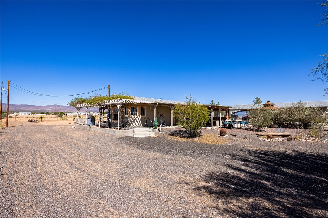 4206 Cordes Road Golden Valley, AZ 86413 - Photo 45 of 60 The property features an extensive gravel driveway, a covered patio with a wooden pergola, and mature trees