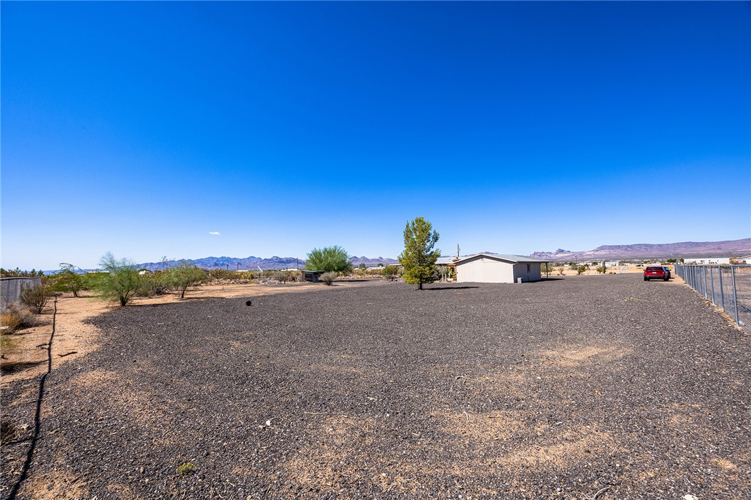 4206 Cordes Road Golden Valley, AZ 86413 - Photo 47 of 60 The property features a spacious gravel lot, a single tree, and a distant view of mountains under a clear sky