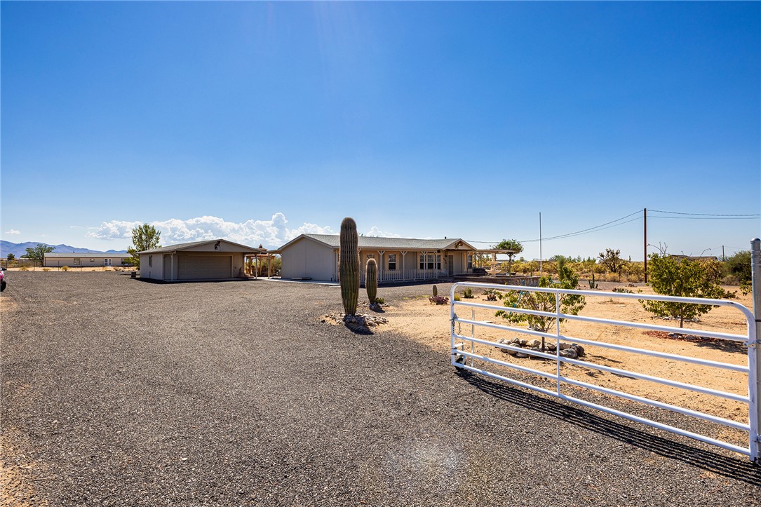 4206 Cordes Road Golden Valley, AZ 86413 - Photo 50 of 60 The property features a gated entrance, a spacious gravel driveway, and a detached garage