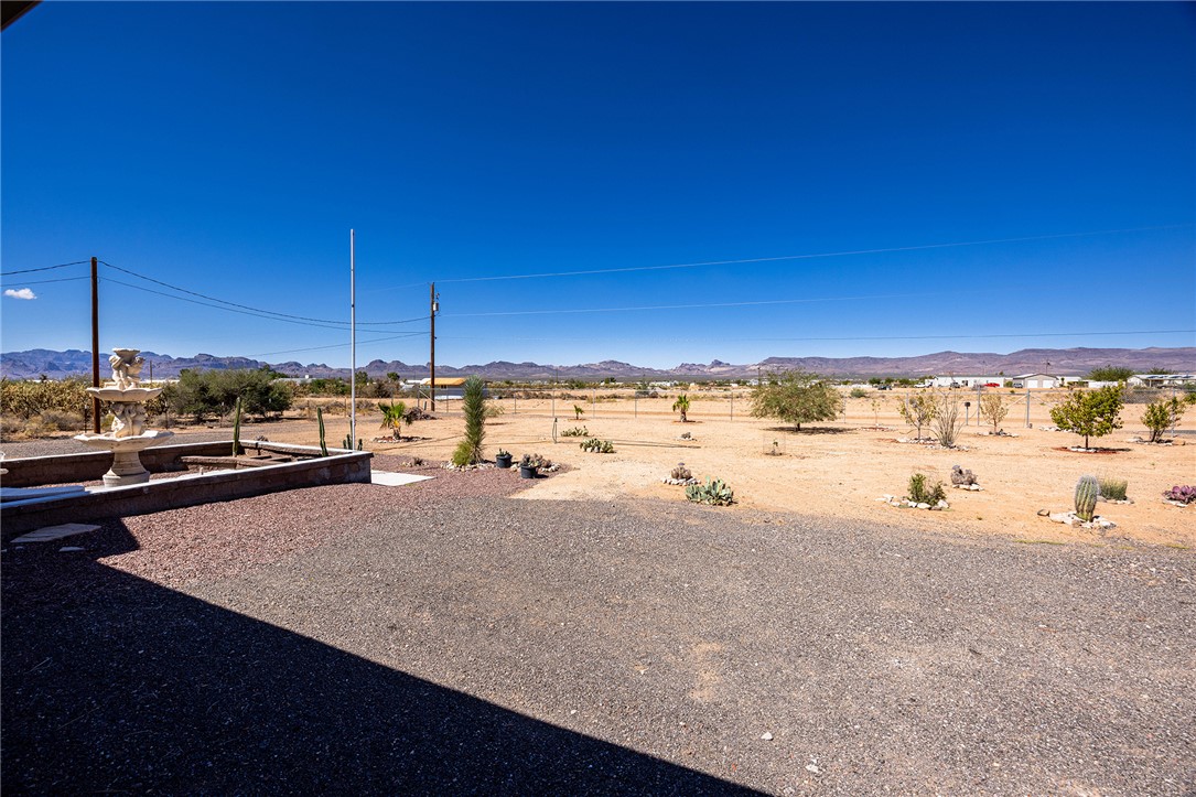 4206 Cordes Road Golden Valley, AZ 86413 - Photo 52 of 60 The property features an expansive gravel area, a decorative fountain, and desert landscaping with various cacti and trees