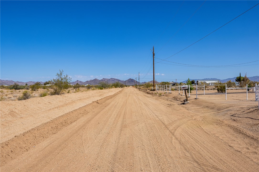 4206 Cordes Road Golden Valley, AZ 86413 - Photo 59 of 60 Expansive desert landscape with a clear blue sky, featuring a long dirt road leading toward distant mountains