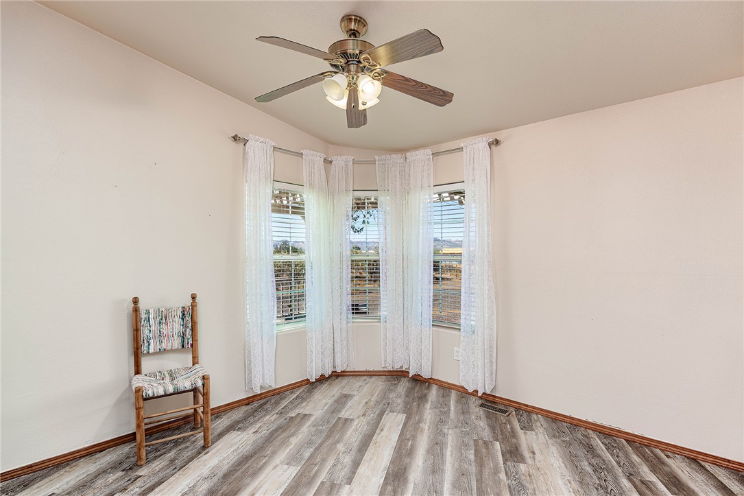 4206 Cordes Road Golden Valley, AZ 86413 - Photo 6 of 60 This room features wood-look flooring, a ceiling fan with integrated lighting, and a bay window with blinds and sheer curtains