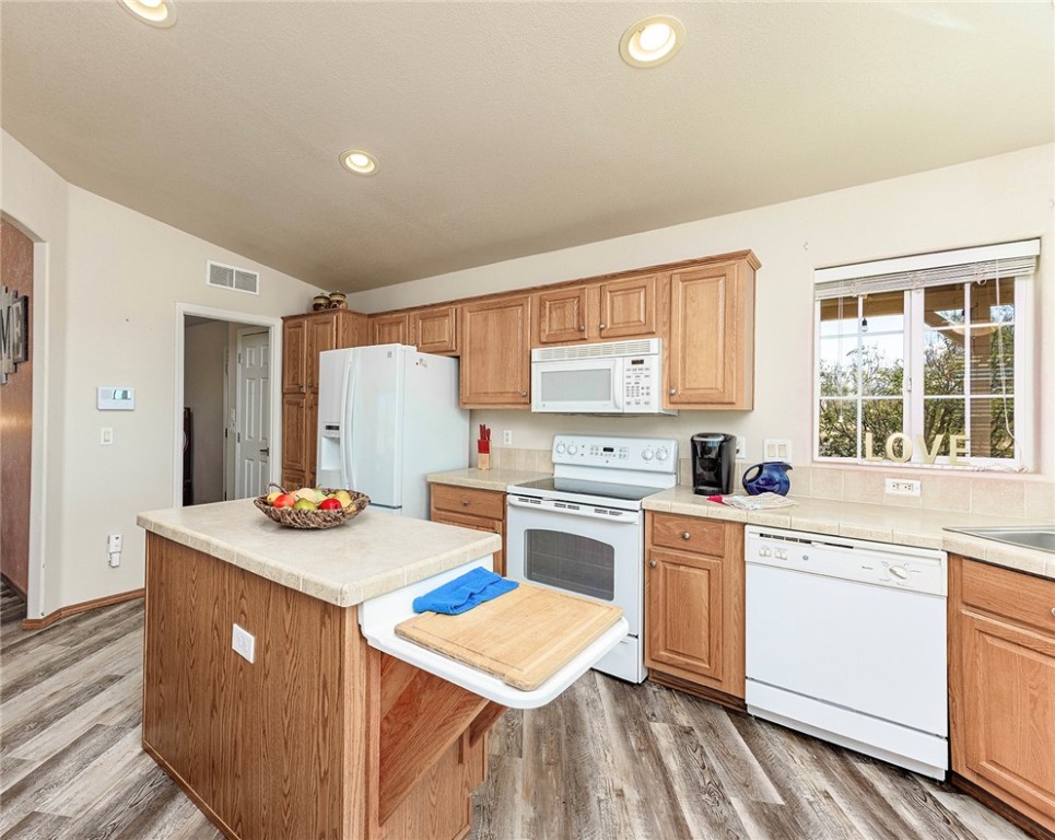 4206 Cordes Road Golden Valley, AZ 86413 - Photo 8 of 60 The kitchen features wood cabinetry, white appliances, recessed lighting, and a window with outdoor views