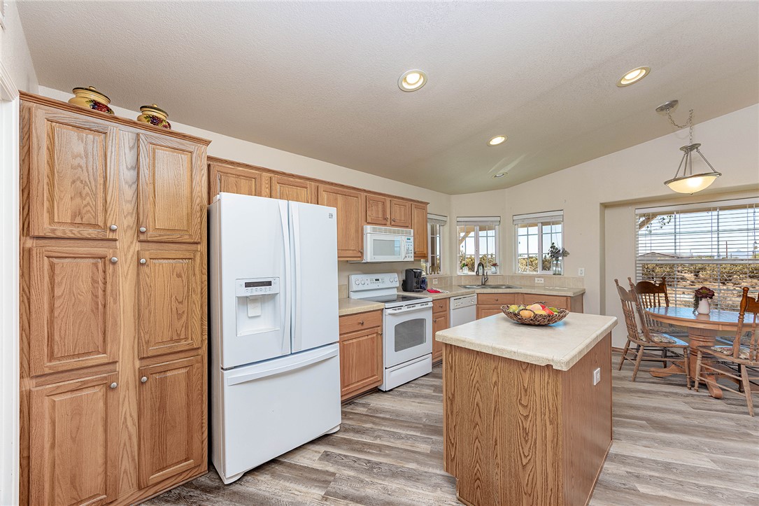 4206 Cordes Road Golden Valley, AZ 86413 - Photo 10 of 60 The kitchen features wood cabinetry, white appliances, recessed lighting, and a kitchen island with a light-colored countertop