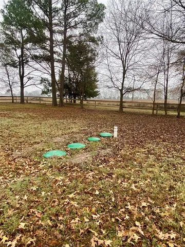 a backyard of a house with large trees and wooden fence