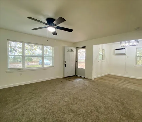 a view of an empty room with window and chandelier fan