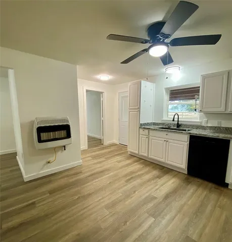 a kitchen with stainless steel appliances kitchen island a sink dishwasher a refrigerator with white cabinets and wooden floor