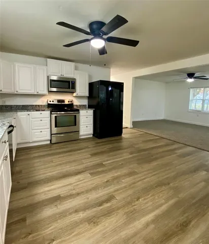 a view of kitchen with microwave stove refrigerator and cabinets