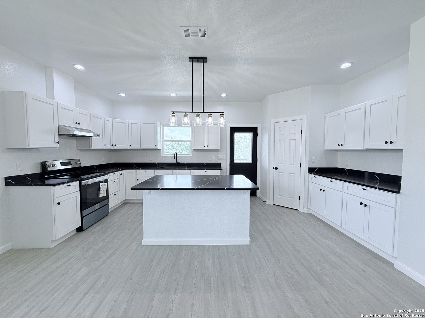 104 Flor Del Sol Road San Antonio, TX 78264 - Photo 1 of 29 a large kitchen with stainless steel appliances a large stove a sink dishwasher a refrigerator and white cabinets with wooden floor