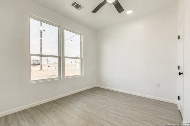an empty room with wooden floor and windows