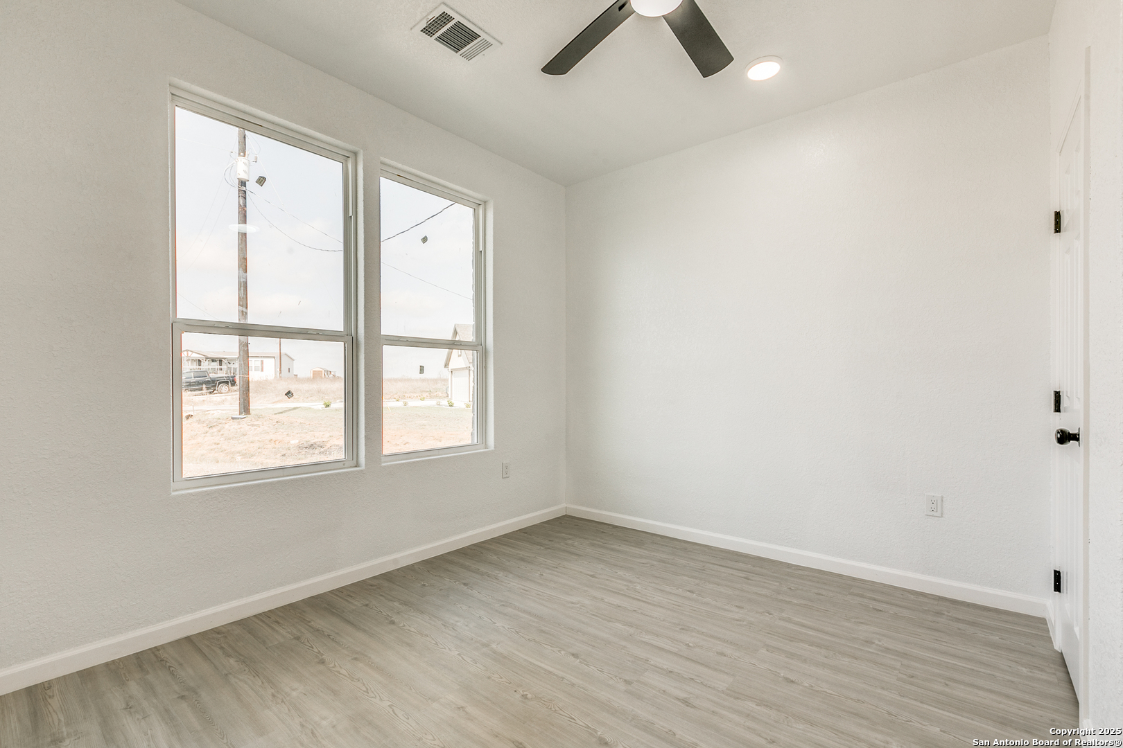 104 Flor Del Sol Road San Antonio, TX 78264 - Photo 12 of 29 an empty room with wooden floor and windows