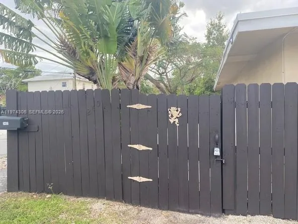 a view of backyard of small house with wooden fence