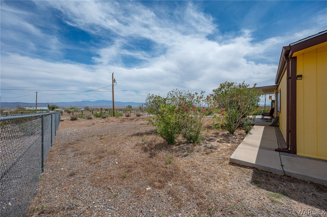 2465 Egar Road Golden Valley, AZ 86413 - Photo 9 of 98 The property features a yellow exterior, a concrete walkway, and established plantings