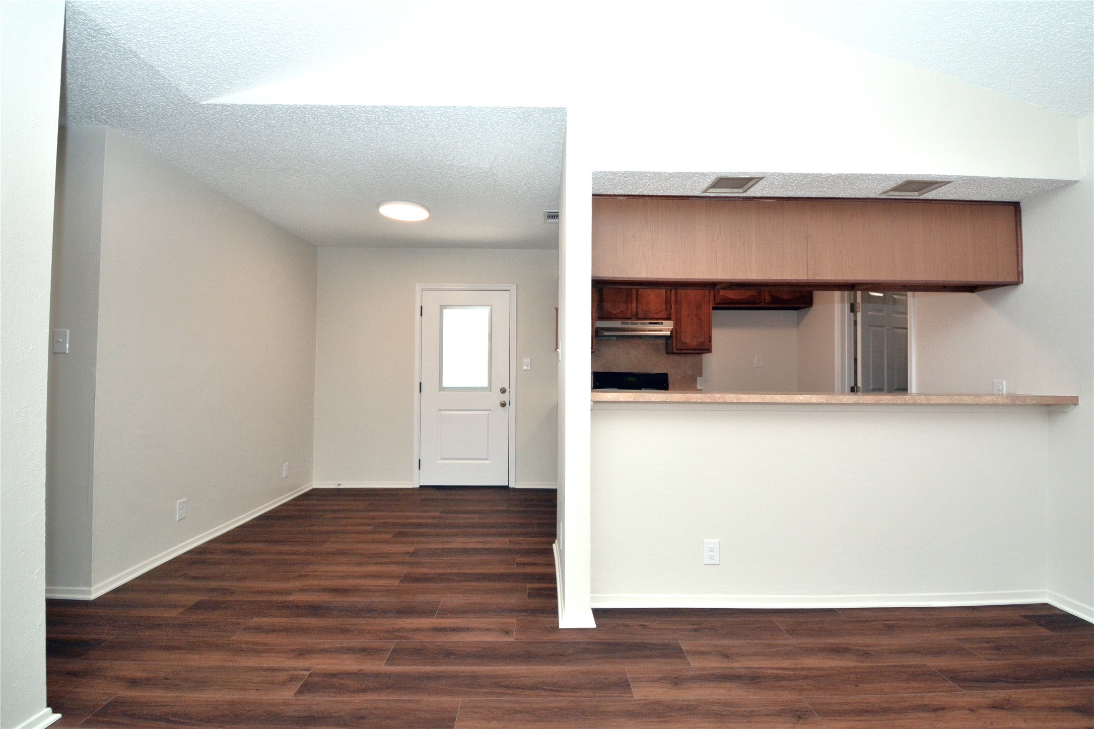 11314 Walnut Ridge Drive, Unit B Austin, TX 78753 - Photo 4 of 19 Rich wood flooring connects an inviting living space to a functional kitchen with warm wood cabinetry.