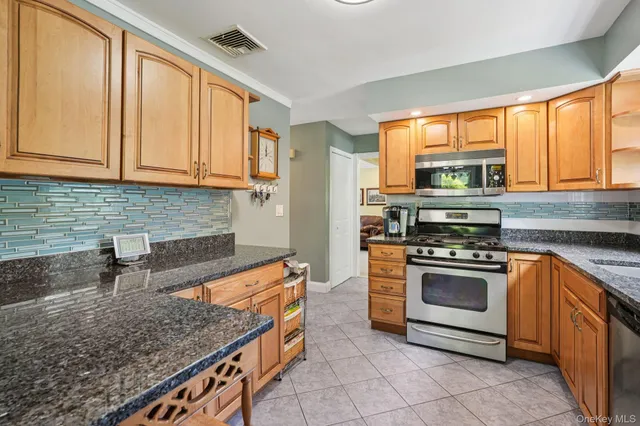 a kitchen with stainless steel appliances granite countertop a sink a stove and a wooden cabinets
