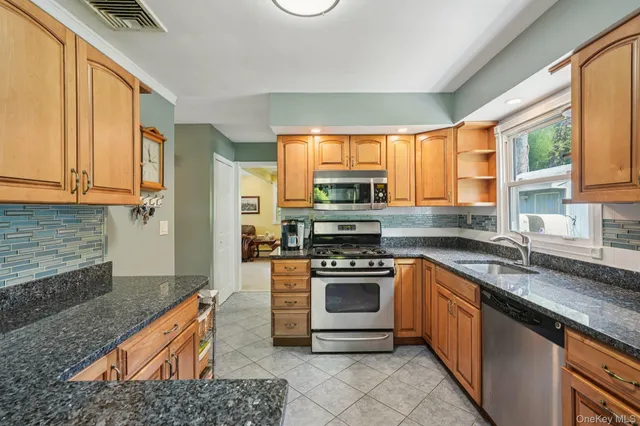 a kitchen with stainless steel appliances granite countertop a stove a sink and a microwave