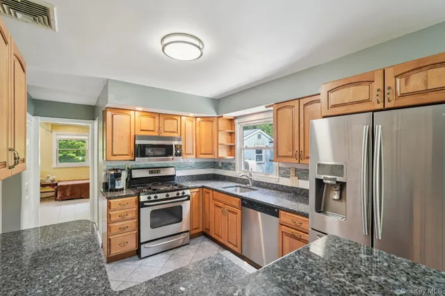 a kitchen with stainless steel appliances granite countertop a stove top oven a sink and a refrigerator