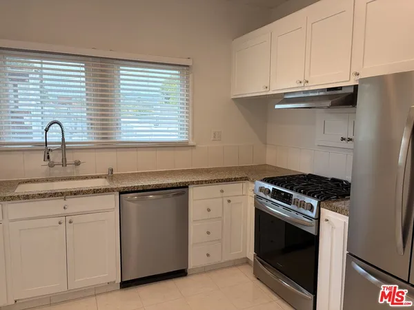 a kitchen with granite countertop white cabinets and a stove